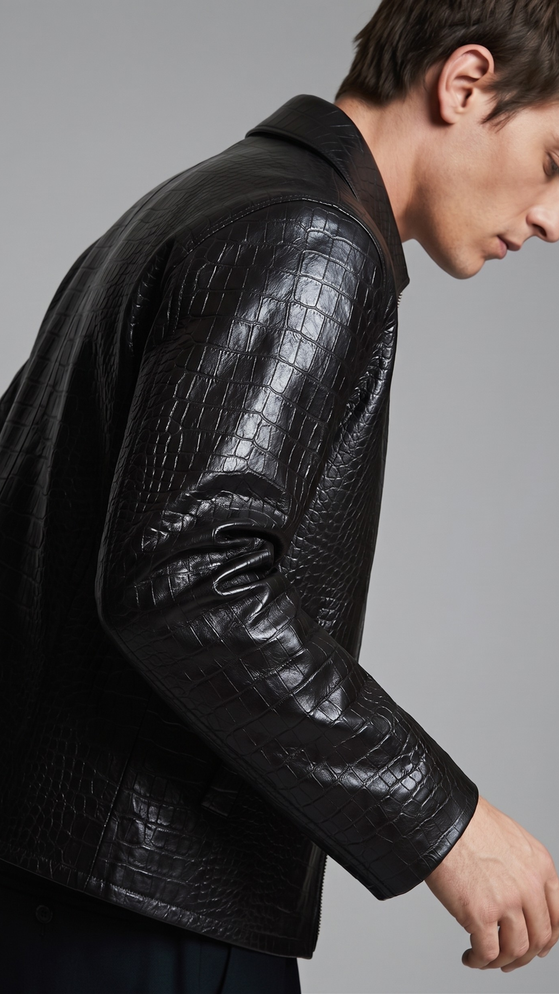 Close-up shot of premium embossed crocodile skin pattern on a black leather jacket.