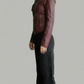 Person wearing a maroon leather jacket and black pants on a plain background