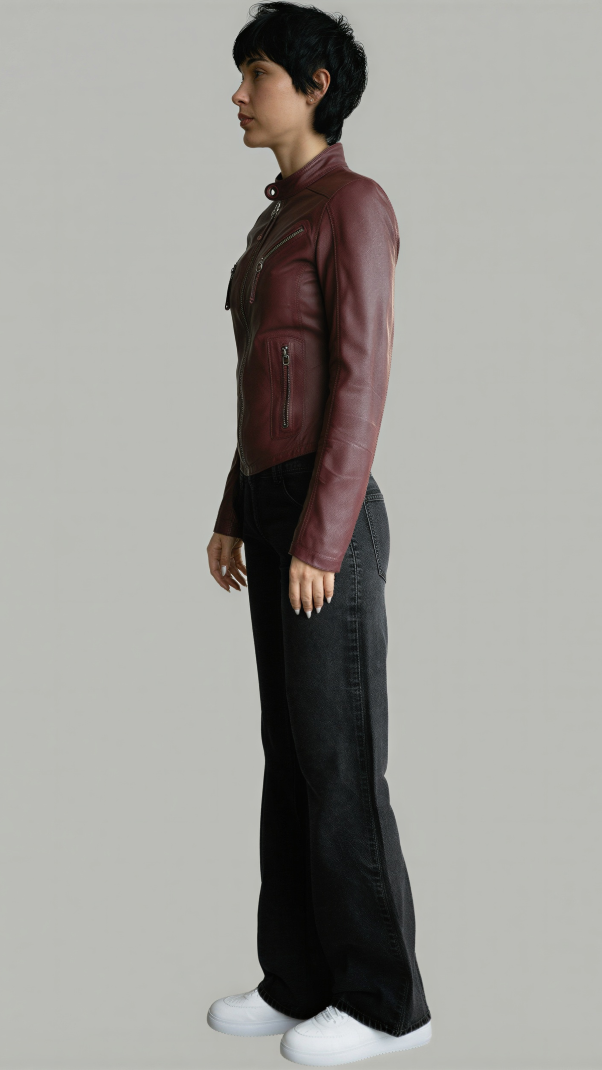 Person wearing a maroon leather jacket and black pants on a plain background