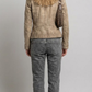 A model shown from the back wearing a cropped burgundy leather jacket with cream stripes on the shoulders and sleeves, paired with dark blue wide-leg jeans and white sneakers, against a solid gray background.