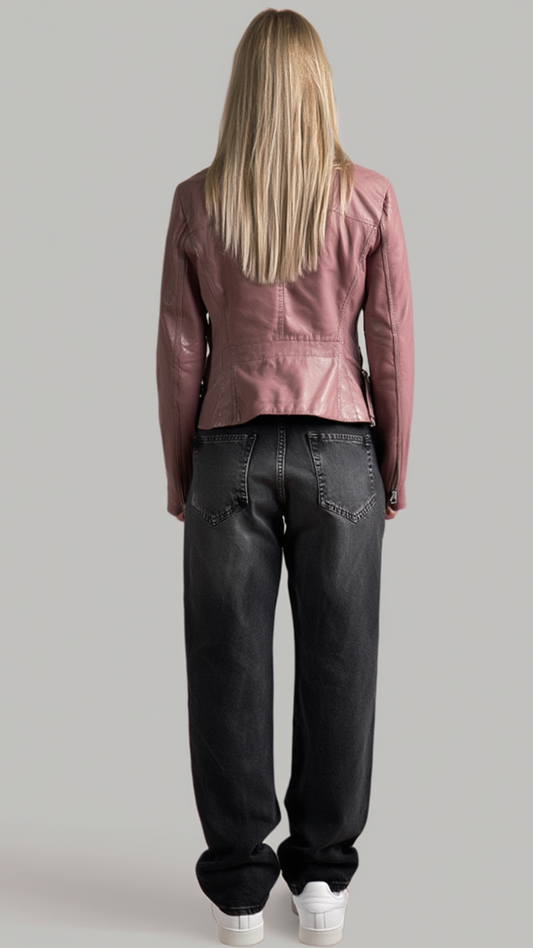 A woman viewed from behind wearing a dusty rose pink peplum leather jacket, dark gray wide-leg jeans, and white sneakers against a solid gray background.
