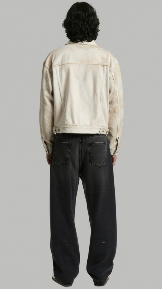 A model shown from the back wearing a cream-colored denim jacket and dark charcoal wide-leg jeans, set against a solid gray studio background.