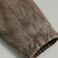 Close-up of brown canvas jacket fabric on a light gray background