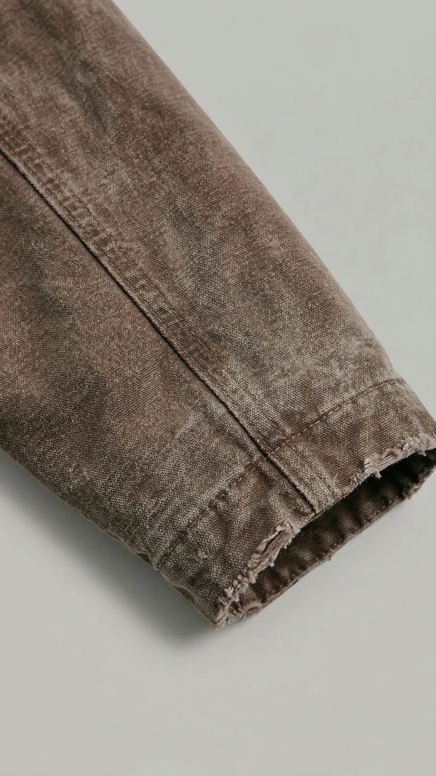 Close-up of brown canvas jacket fabric on a light gray background