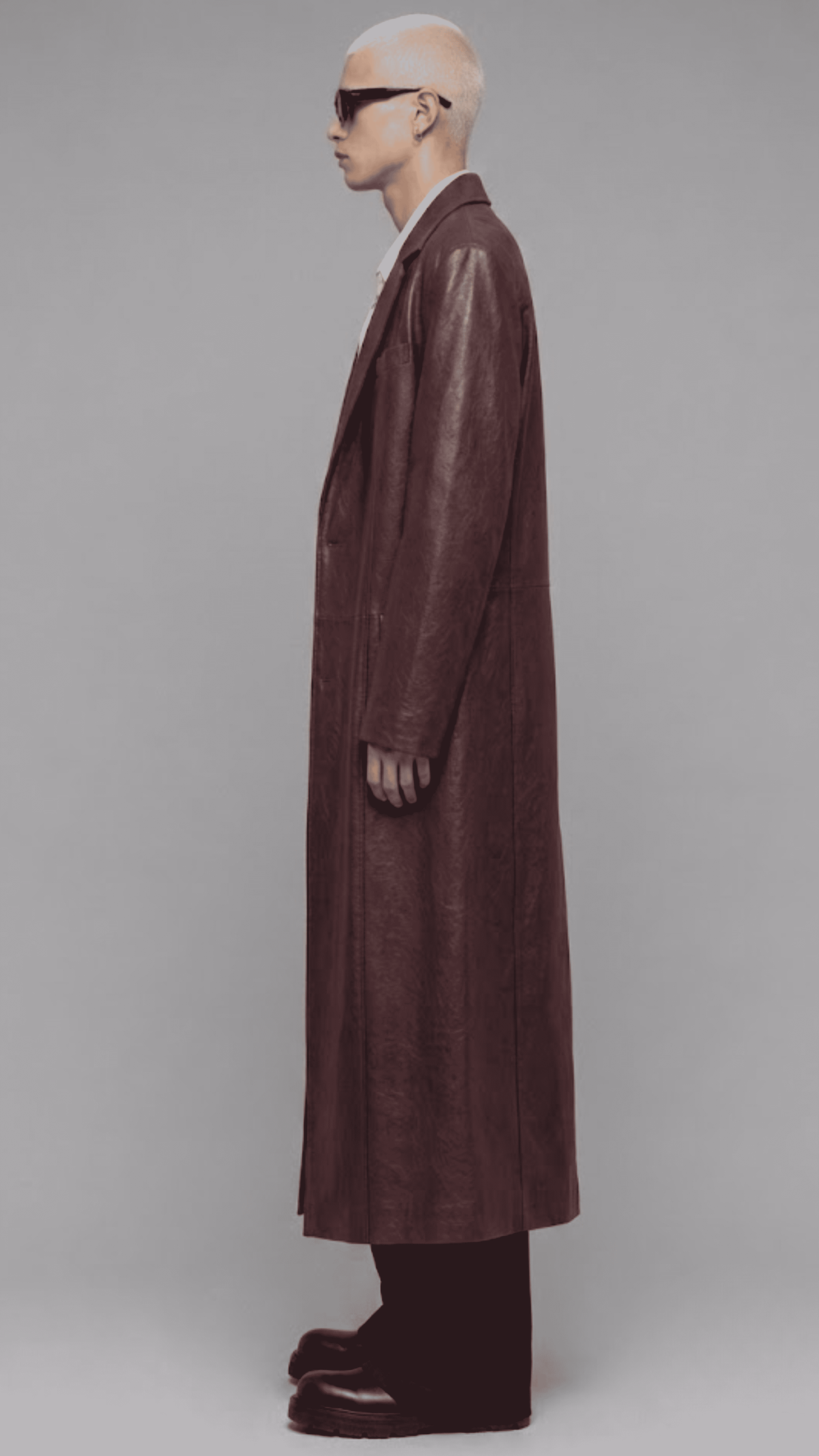 Side angle of model wearing jackero dark red vine leather trench coat showing full flowy silhouette and sleeve cuff construction