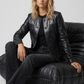Women's sophisticated high-fashion featuring a structured full-length black leather duster coat styled effortlessly for an edgy street-luxe look.