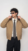 Men's tan canvas bomber jackero jacket with brown leather collar styled over a white dress shirt and striped tie