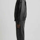 Side angle view showing waist slash pockets and structured panel stitching on loose fit black leather jacket.