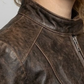 Close-up micro detail focusing on the rugged, worn-in texture and faded seams of the dark chocolate brown distressed genuine leather.