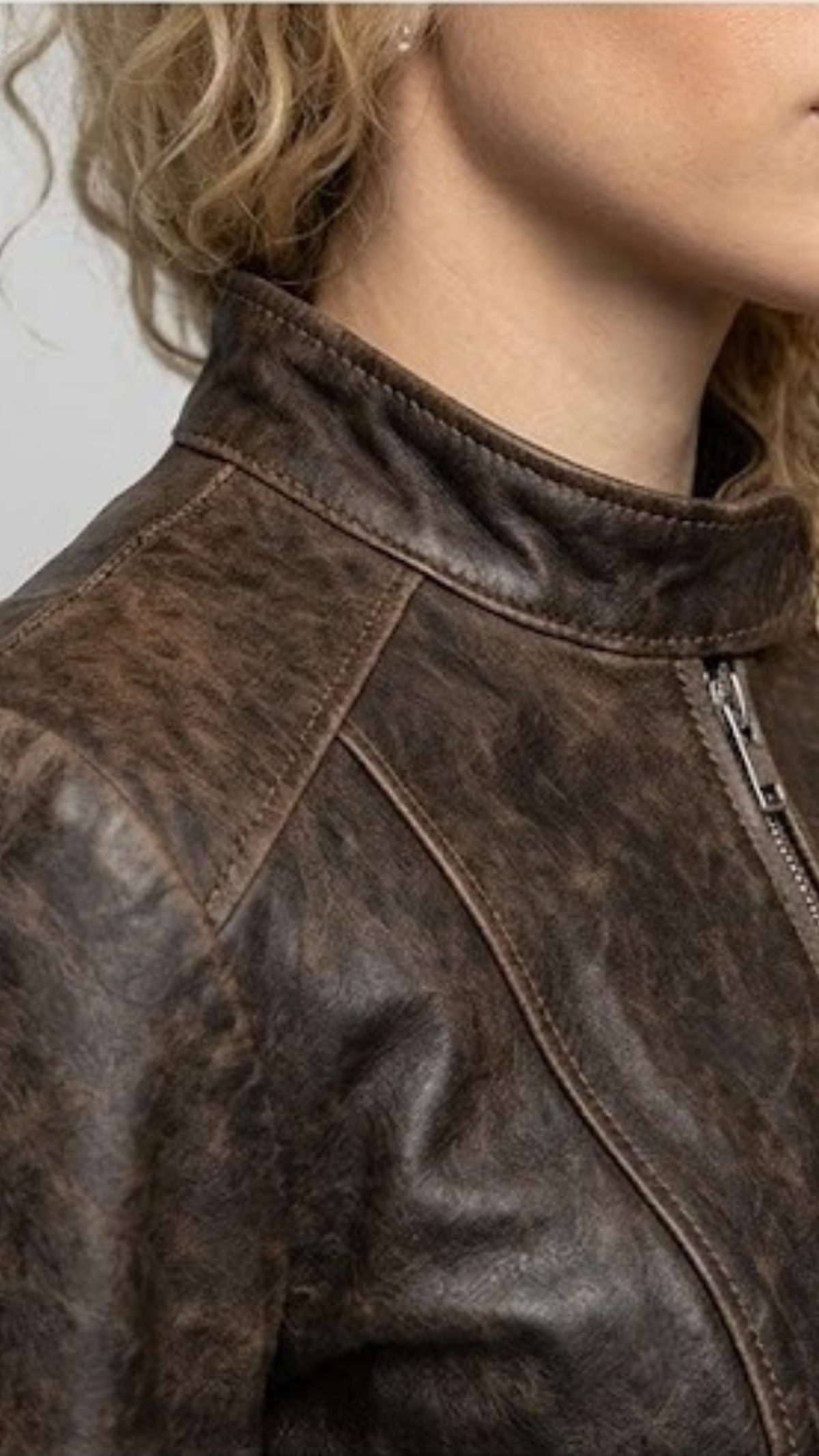 Close-up micro detail focusing on the rugged, worn-in texture and faded seams of the dark chocolate brown distressed genuine leather.