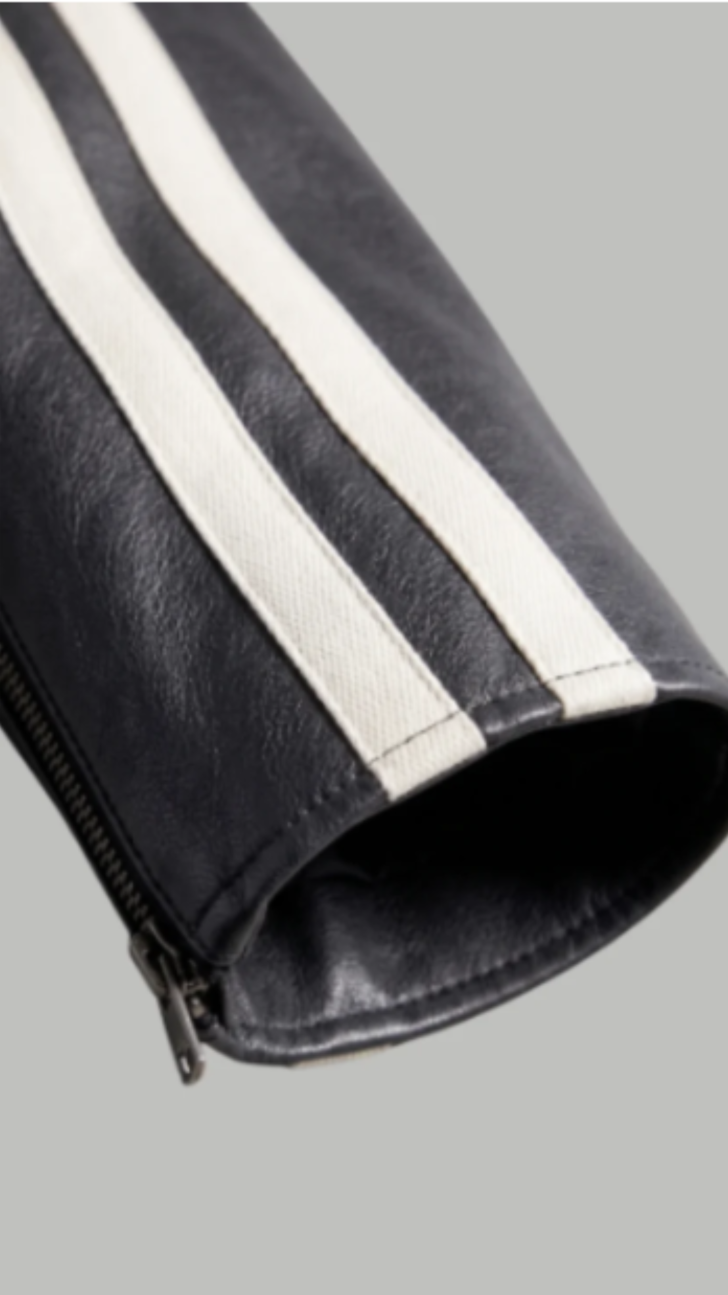 Close-up of a black leather jacket with white stripes on a gray background