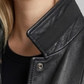 Close-up of a person wearing a black leather jacket with a blurred background
