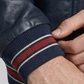 Close-up of a person wearing a dark blue jacket with a striped sleeve cuff.