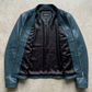 E-commerce product flat lay presentation featuring the contemporary dark cyan leather jacket neatly laid out on a professional studio backdrop.