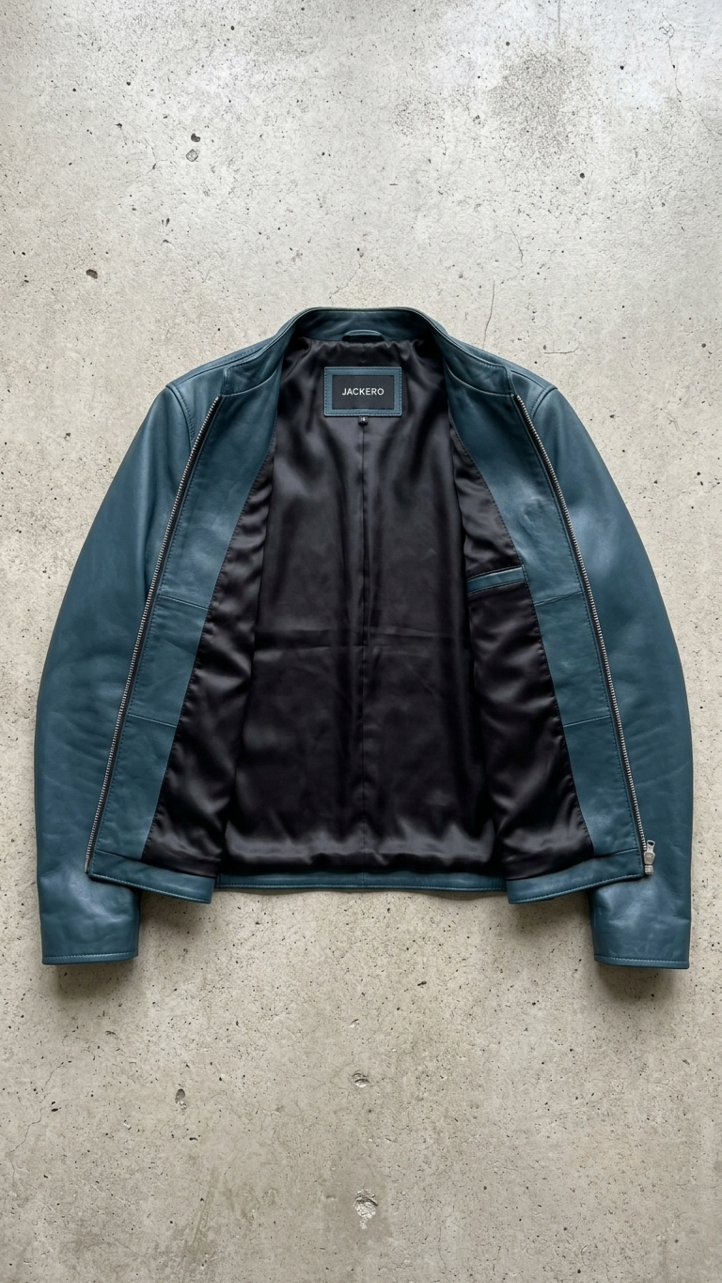 E-commerce product flat lay presentation featuring the contemporary dark cyan leather jacket neatly laid out on a professional studio backdrop.