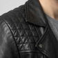 Macro detailed focus capture showing the authentic full-grain texture and high-shine silver metal hardware on the jet black leather jacket.