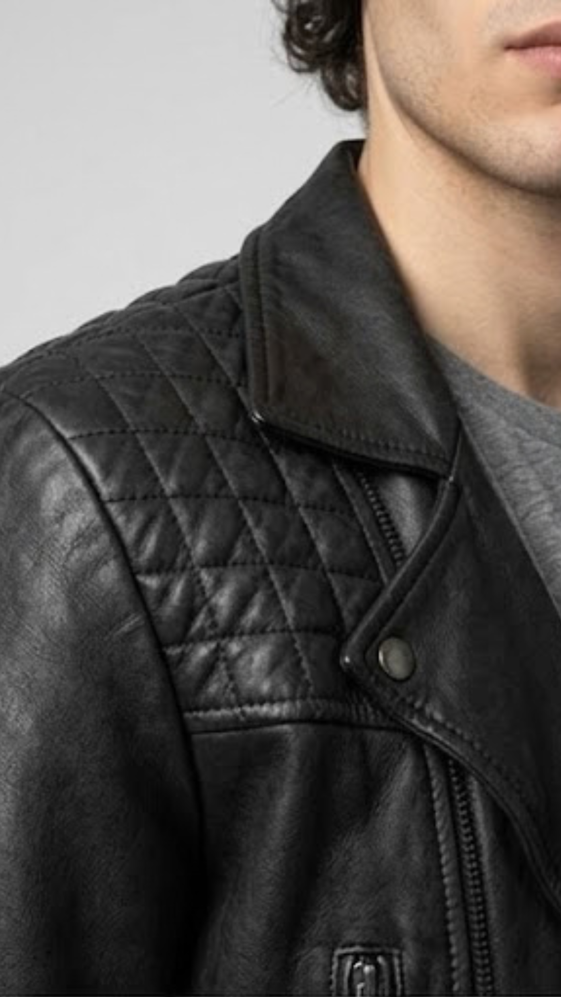 Macro detailed focus capture showing the authentic full-grain texture and high-shine silver metal hardware on the jet black leather jacket.