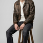 Rugged men's outdoor lifestyle photography showcasing a casual timeless outfit anchored by a luxury vintage brown leather pilot coat.