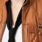 Macro detailed focus capture showing the authentic tawny brown leather grain surface paired with premium heavy industrial metallic zippers.