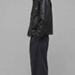 Side profile view displaying the relaxed slouchy baggy silhouette and comfortable broad shoulder drop of a dark black leather coat.