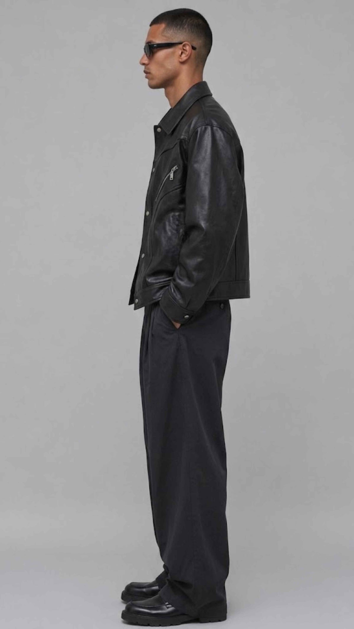 Side profile view displaying the relaxed slouchy baggy silhouette and comfortable broad shoulder drop of a dark black leather coat.