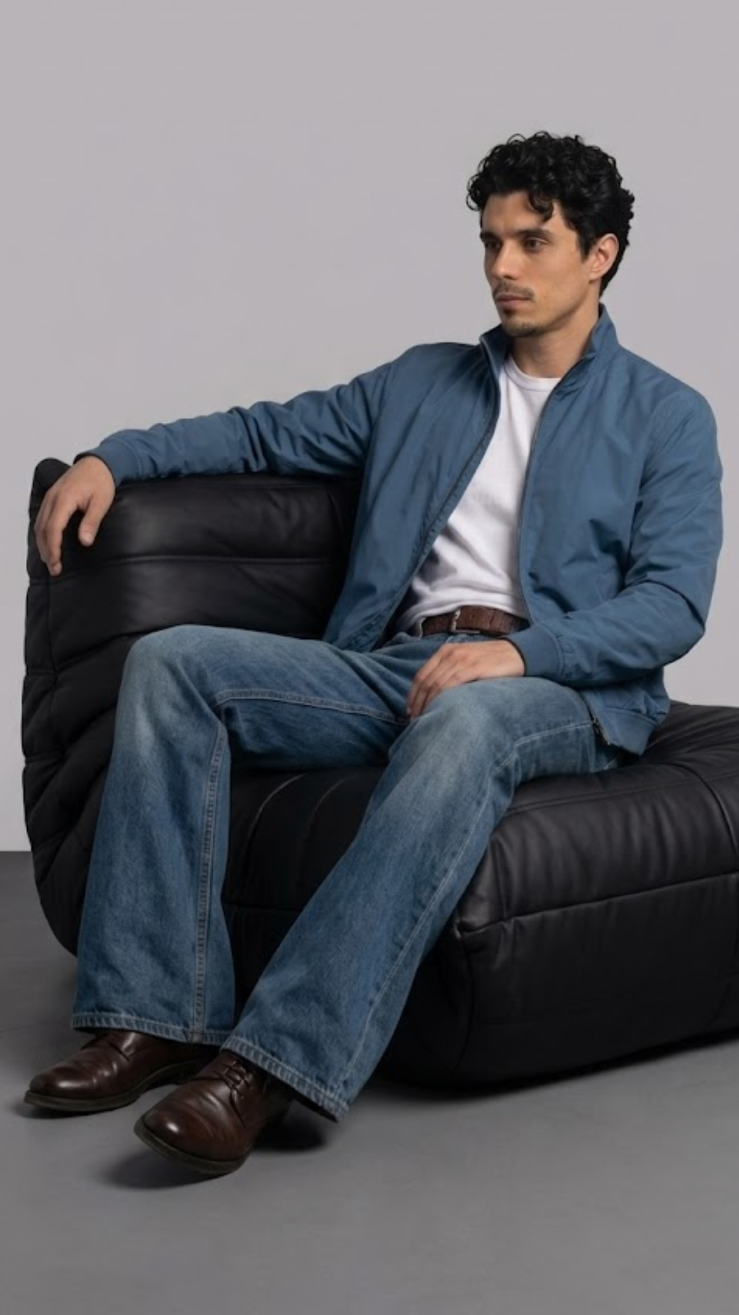 Men's contemporary high-fashion statement featuring a sleek turquoise silk cotton bomber jacket styled for an upscale casual look.