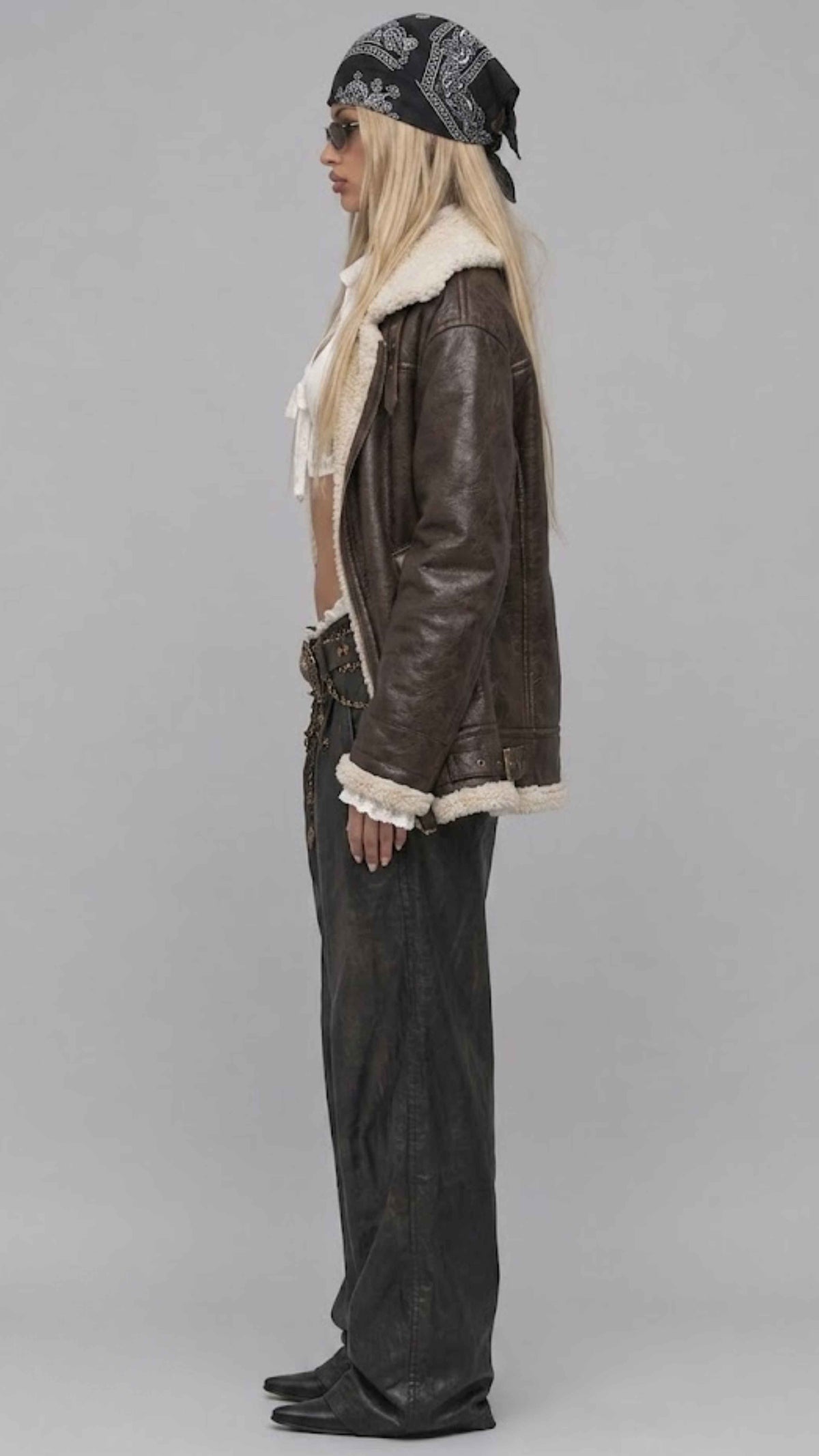 Side-angle profile view displaying the comfortable relaxed Y2K baggy fit of a men's dark brown leather bomber with soft shearling accents.