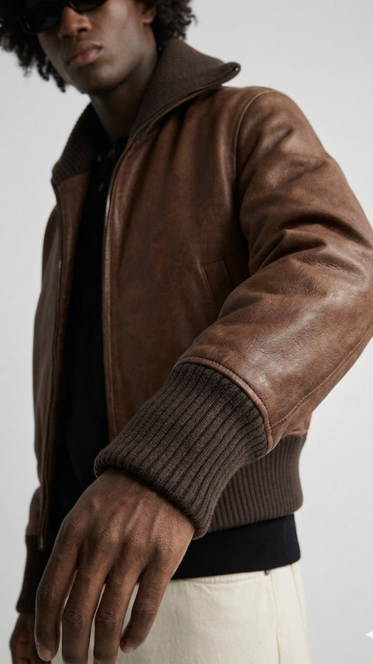 Macro detailed focus capture displaying the soft premium texture and deep dark cocoa tone of the genuine leather bomber jacket fabric.