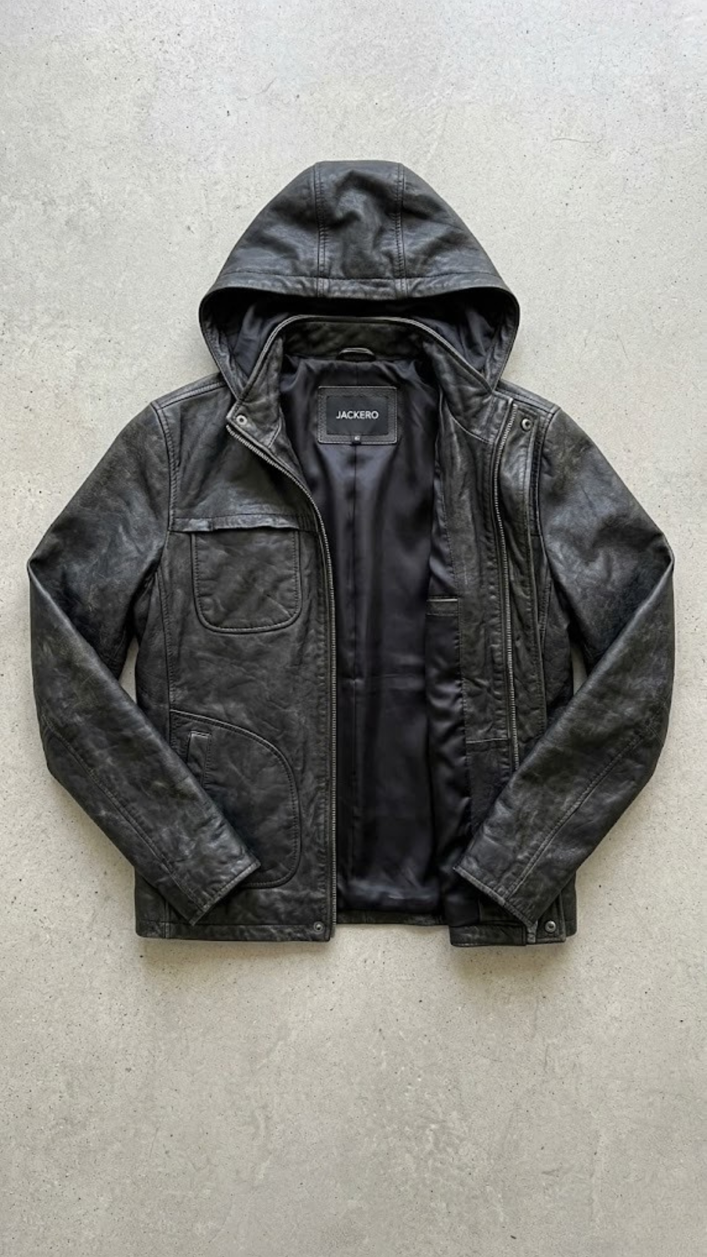 Jackero jacket flat lay photography showing the interior lining and clean design of a premium black leather jacket with an attached hood.