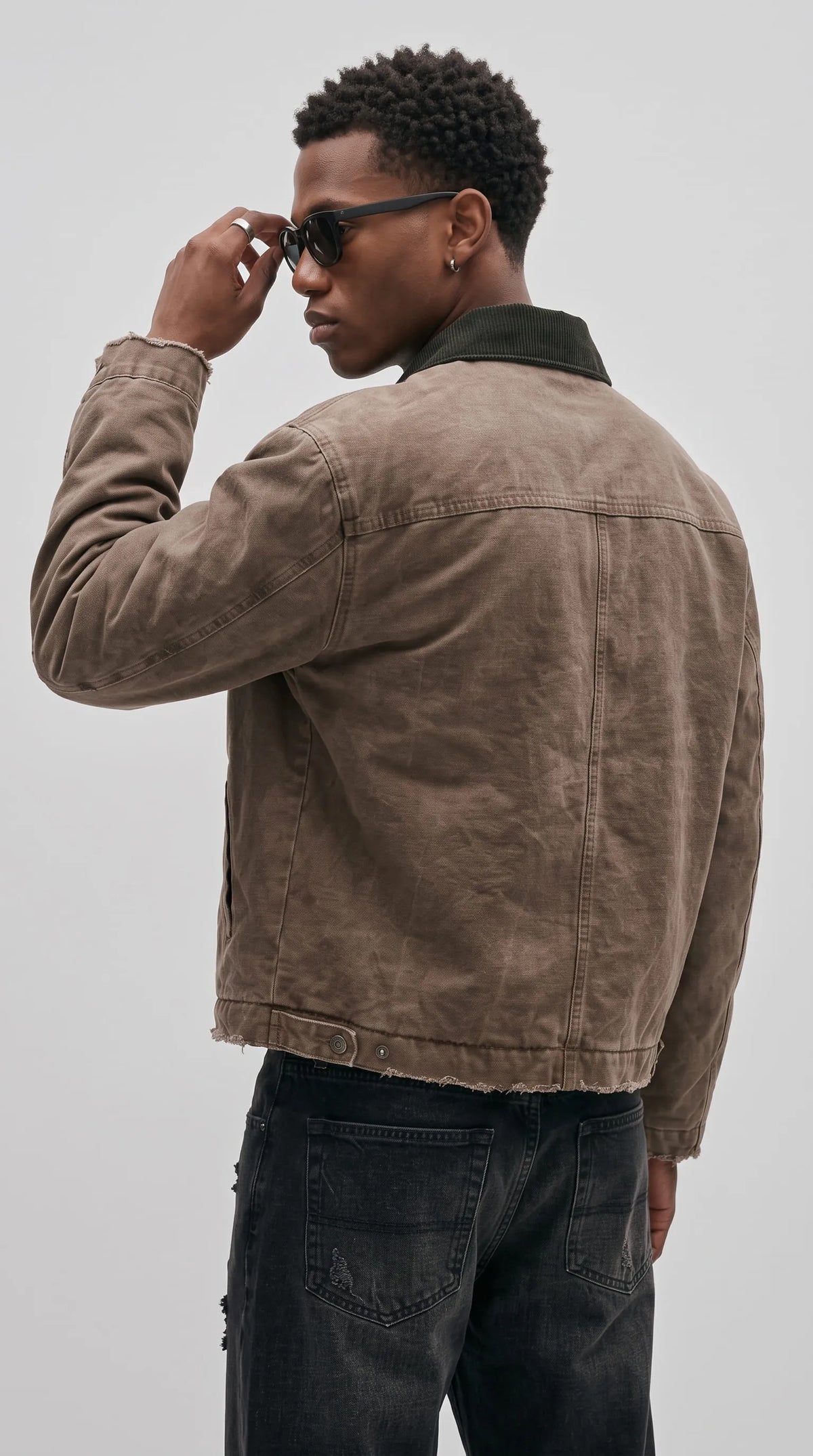Vintage-inspired brown cotton canvas work jacket with a panelled shoulder yoke, visible construction seams, a weathered earthy finish and a dark corduroy collar, delivering an authentic heritage workwear style.