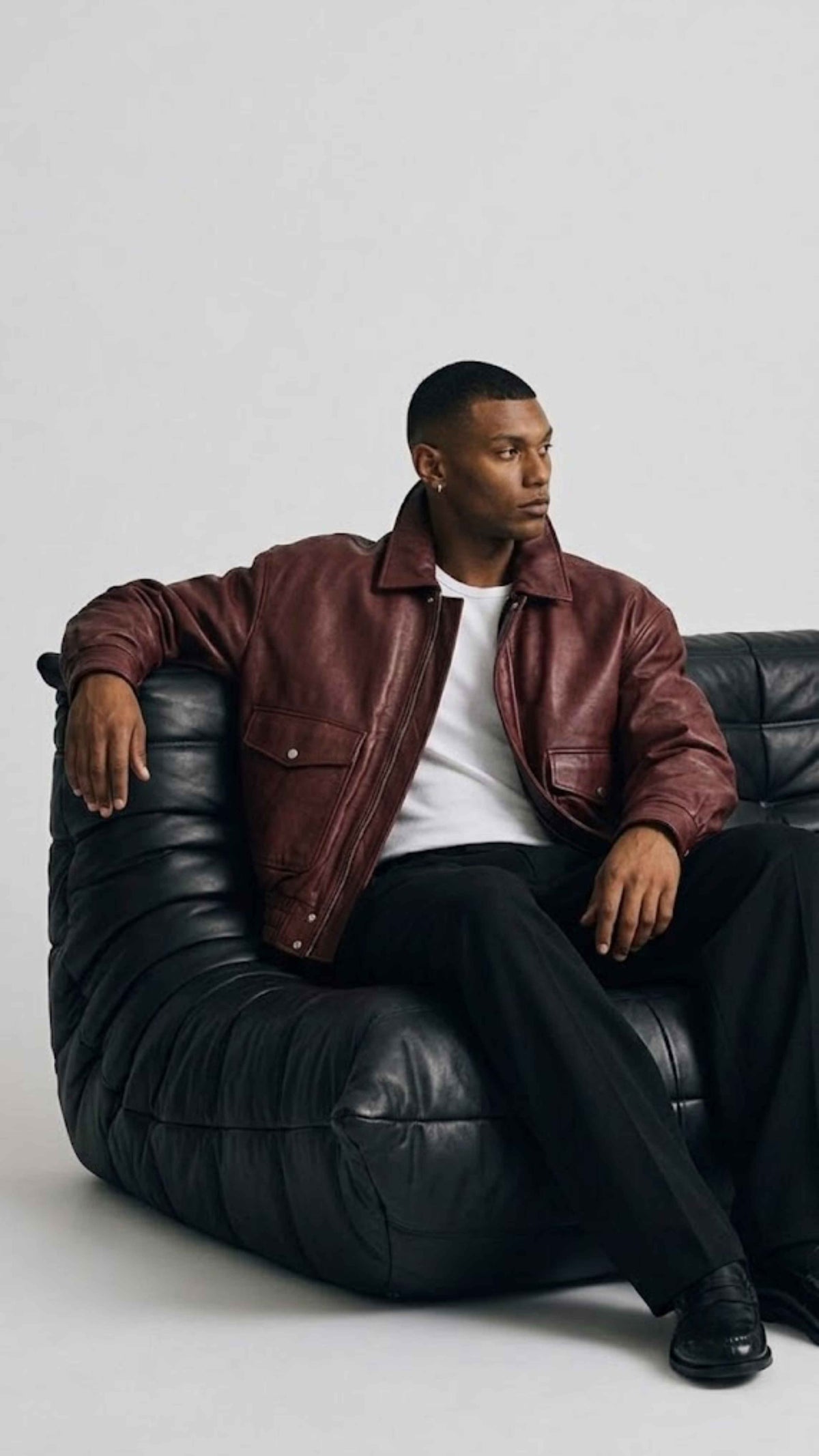 Detailed view of side waist slash pockets and flexible elasticated ribbed cuffs on maroon leather outerwear.
