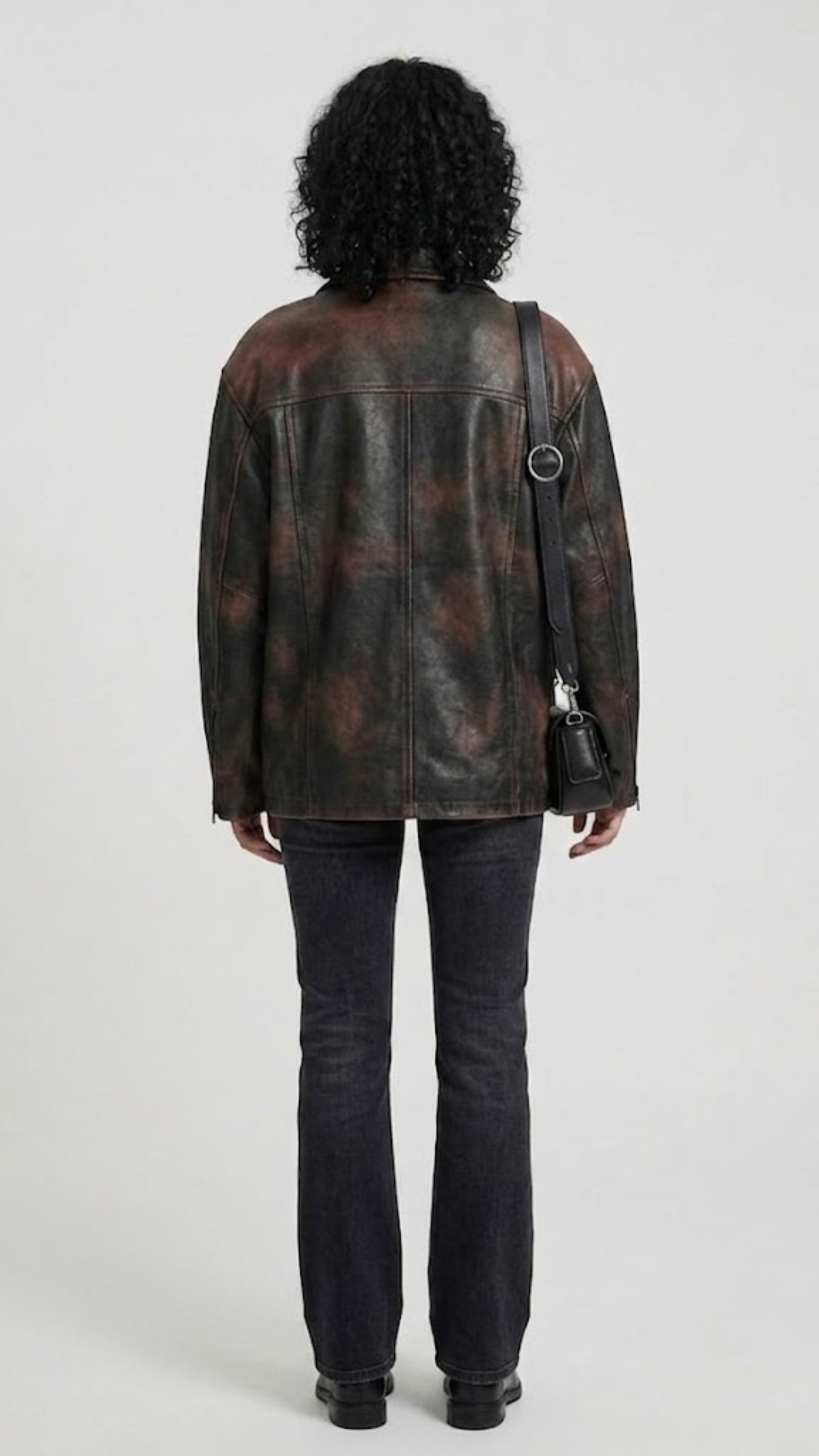 Straight-on back view of a minimalist black leather trucker jacket showcasing its structured paneling and tailored vintage look.