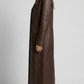 Studio photography showcasing the structured silhouette of a long leather trench coat.