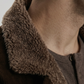 Close-up of a person wearing a dark brown jacket with a textured fur collar.