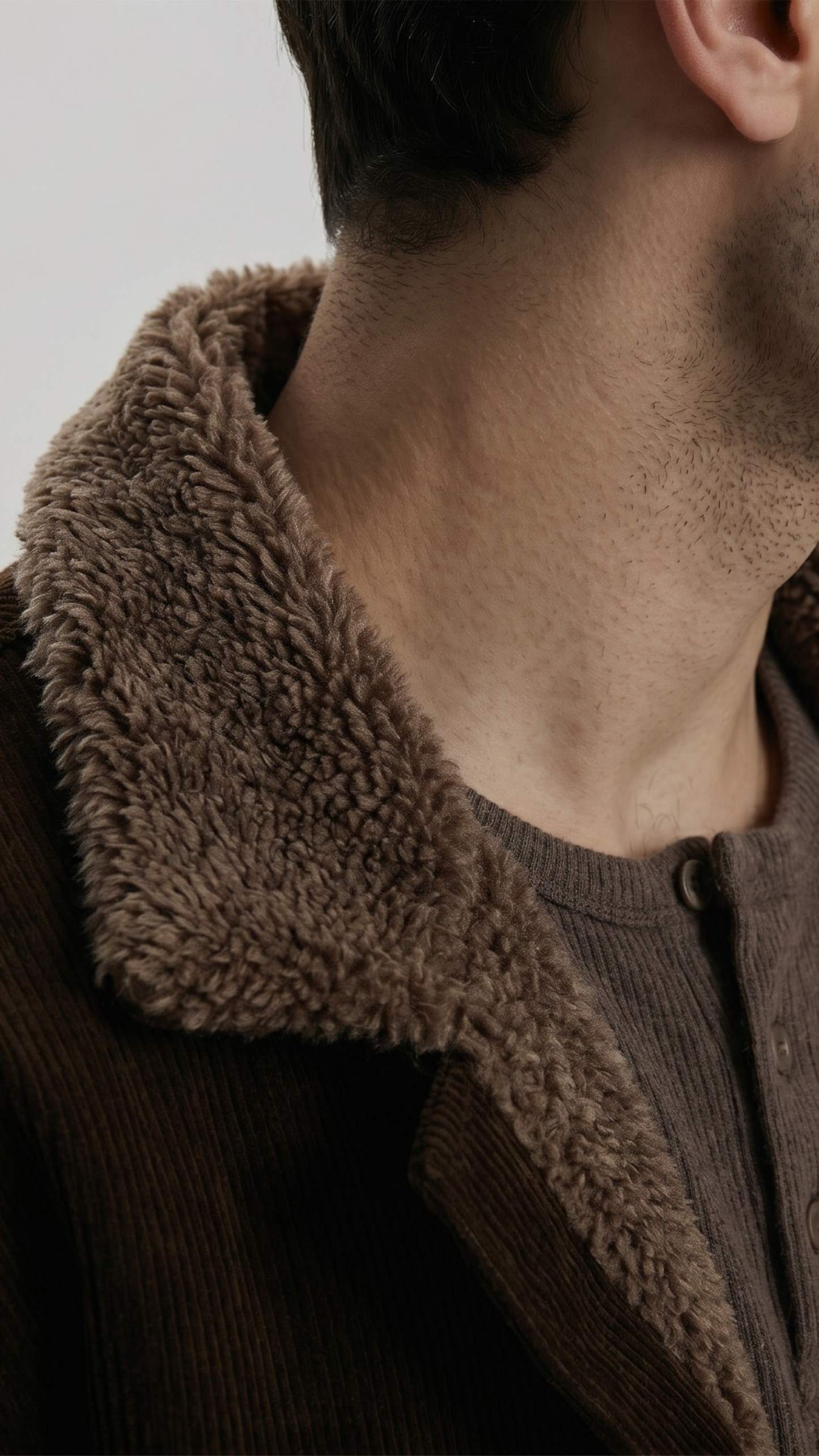 Close-up of a person wearing a dark brown jacket with a textured fur collar.