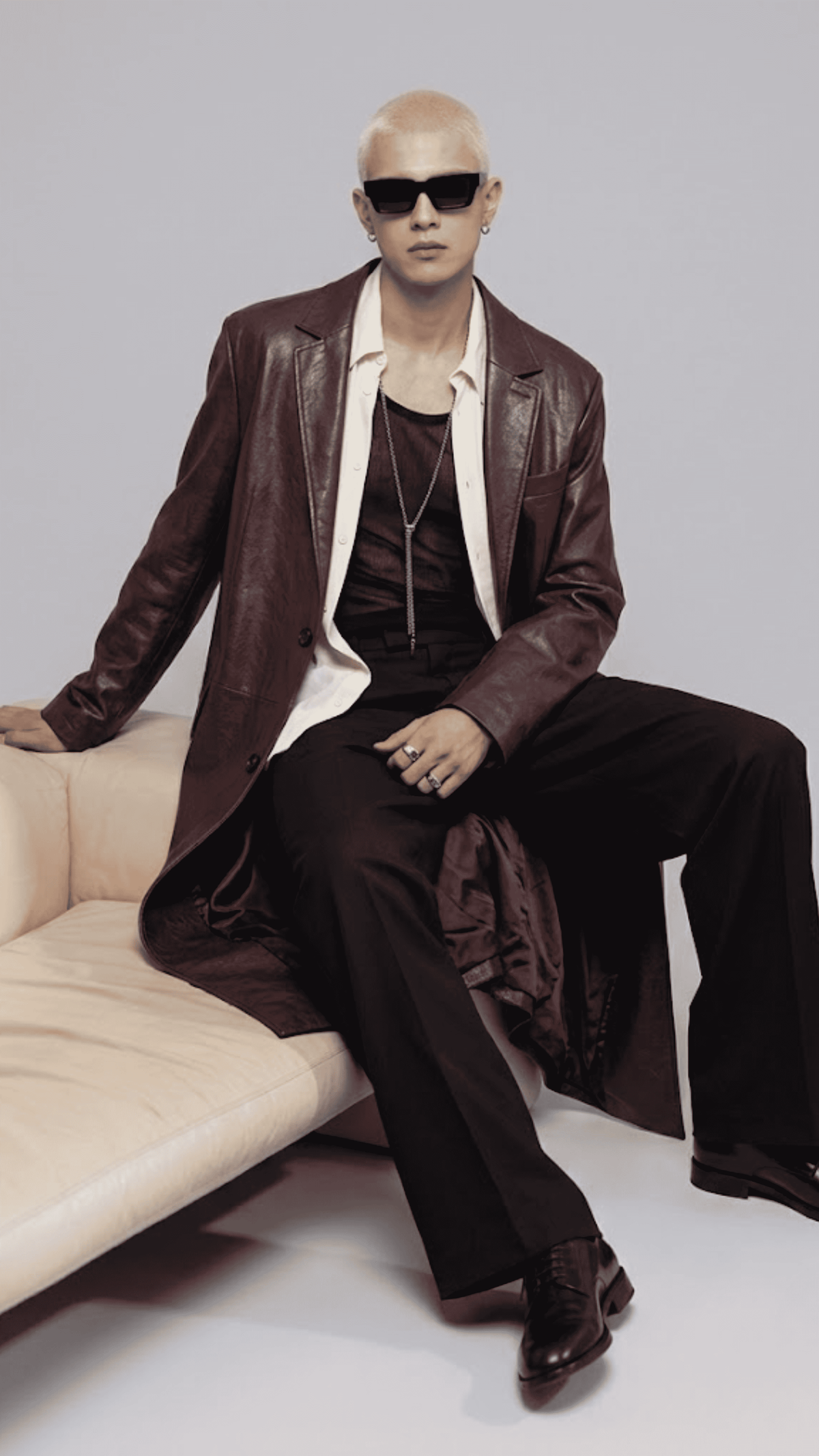 Detailed view of dark red leather waist belt buckle and side pockets on a long leather trench coat