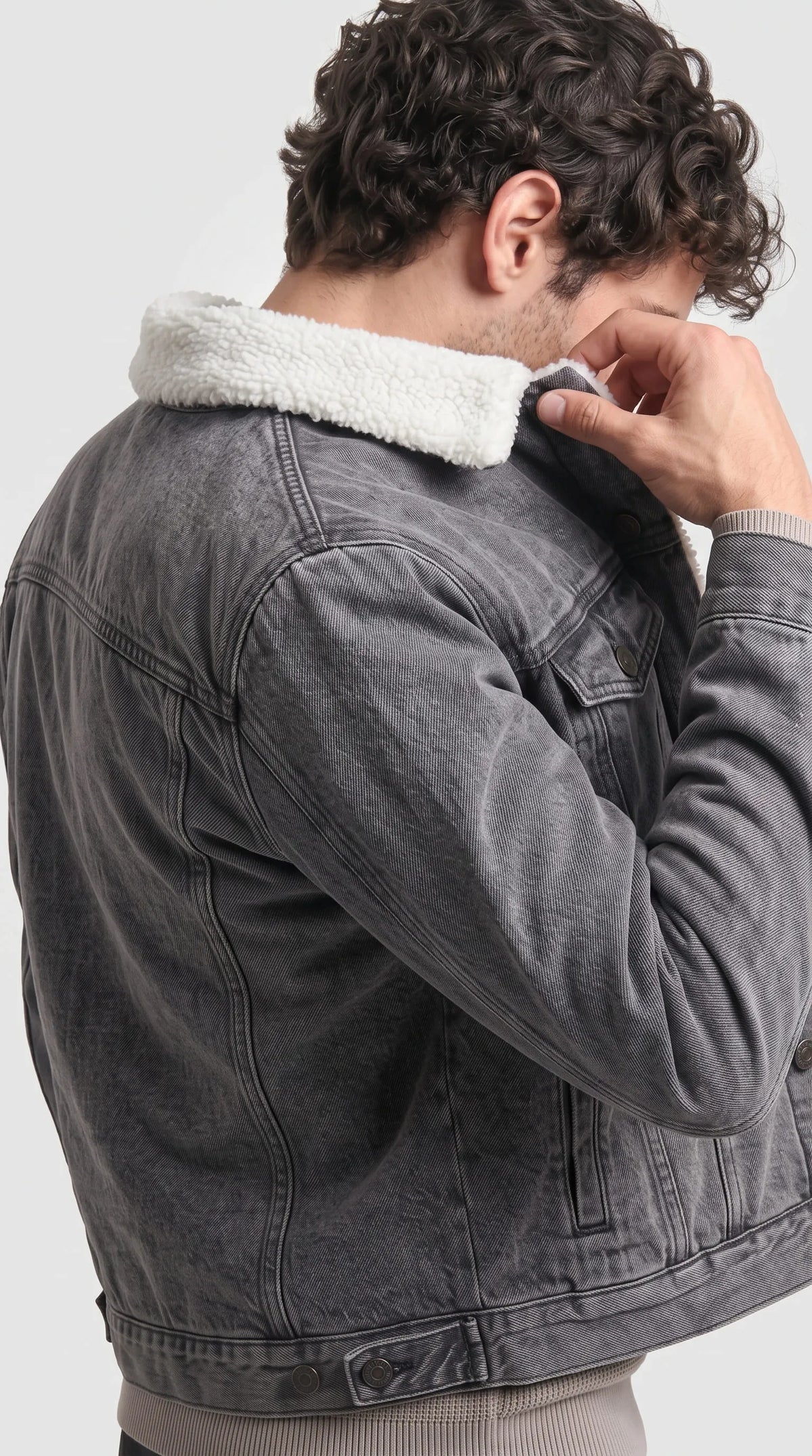 This Jackero vintage washed grey jean coat combines an edgy streetwear aesthetic with a cozy faux sherpa lining, creating a striking and engaging look for fashion-forward individuals braving the cold.
