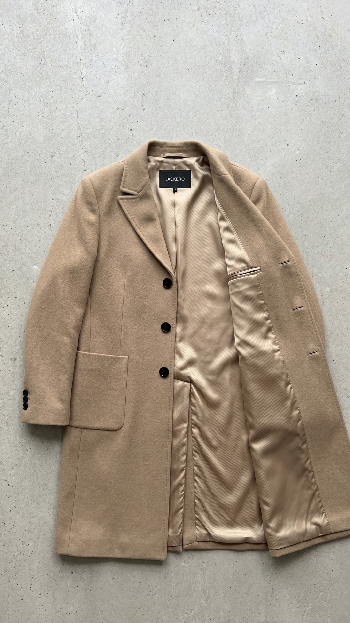 Detailed look at the button closure and clean lines of a camel-colored long winter coat.