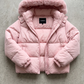 a pastel pink puffer jacket highlighting the high-quality zipper, soft fabric, and premium faux fur hood details.
