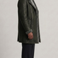 Side profile of a premium long leather trench coat in dark grey with visible shearling accents.