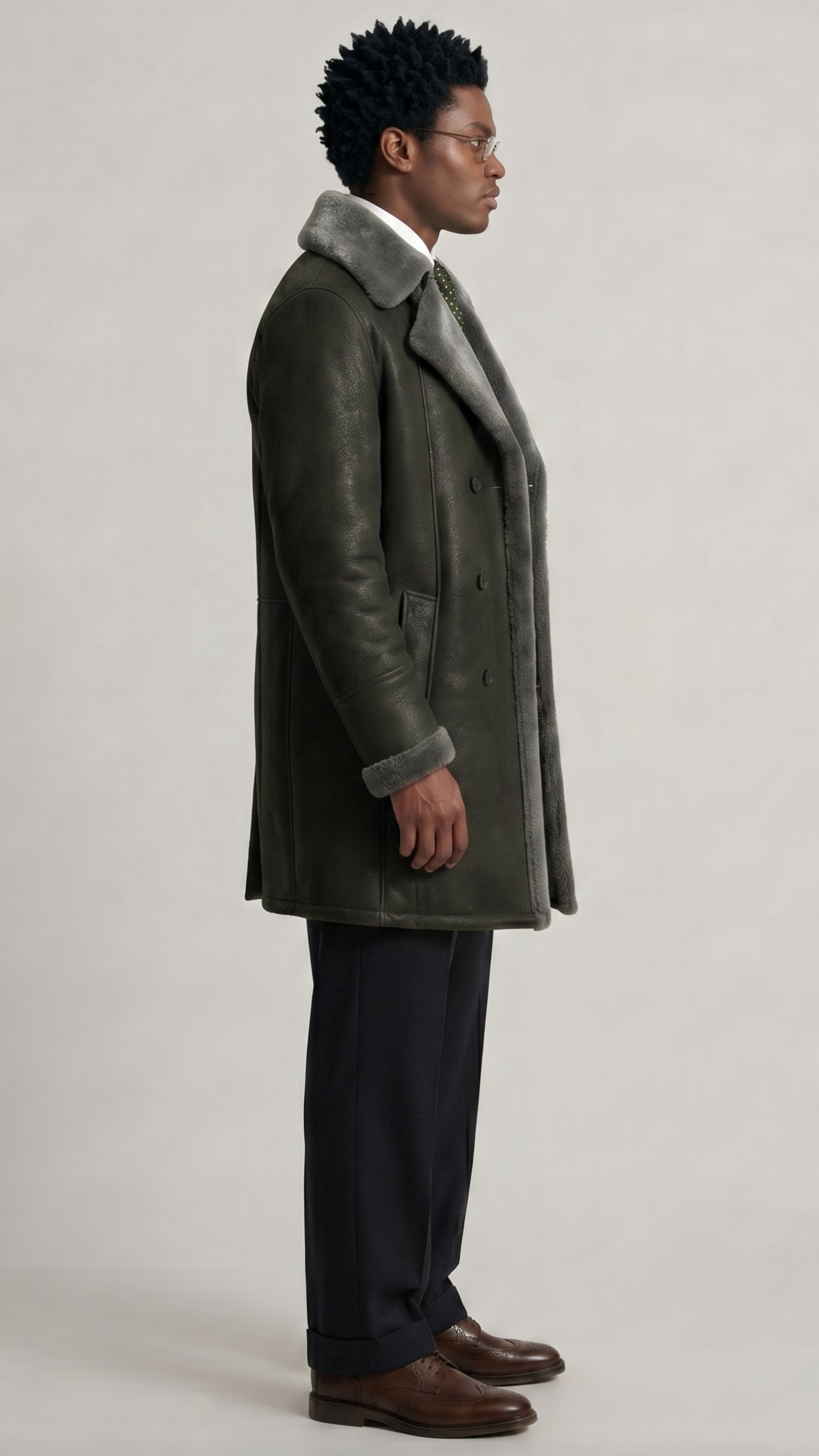 Side profile of a premium long leather trench coat in dark grey with visible shearling accents.