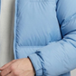 Light blue puffer jacket worn by a person on a neutral background