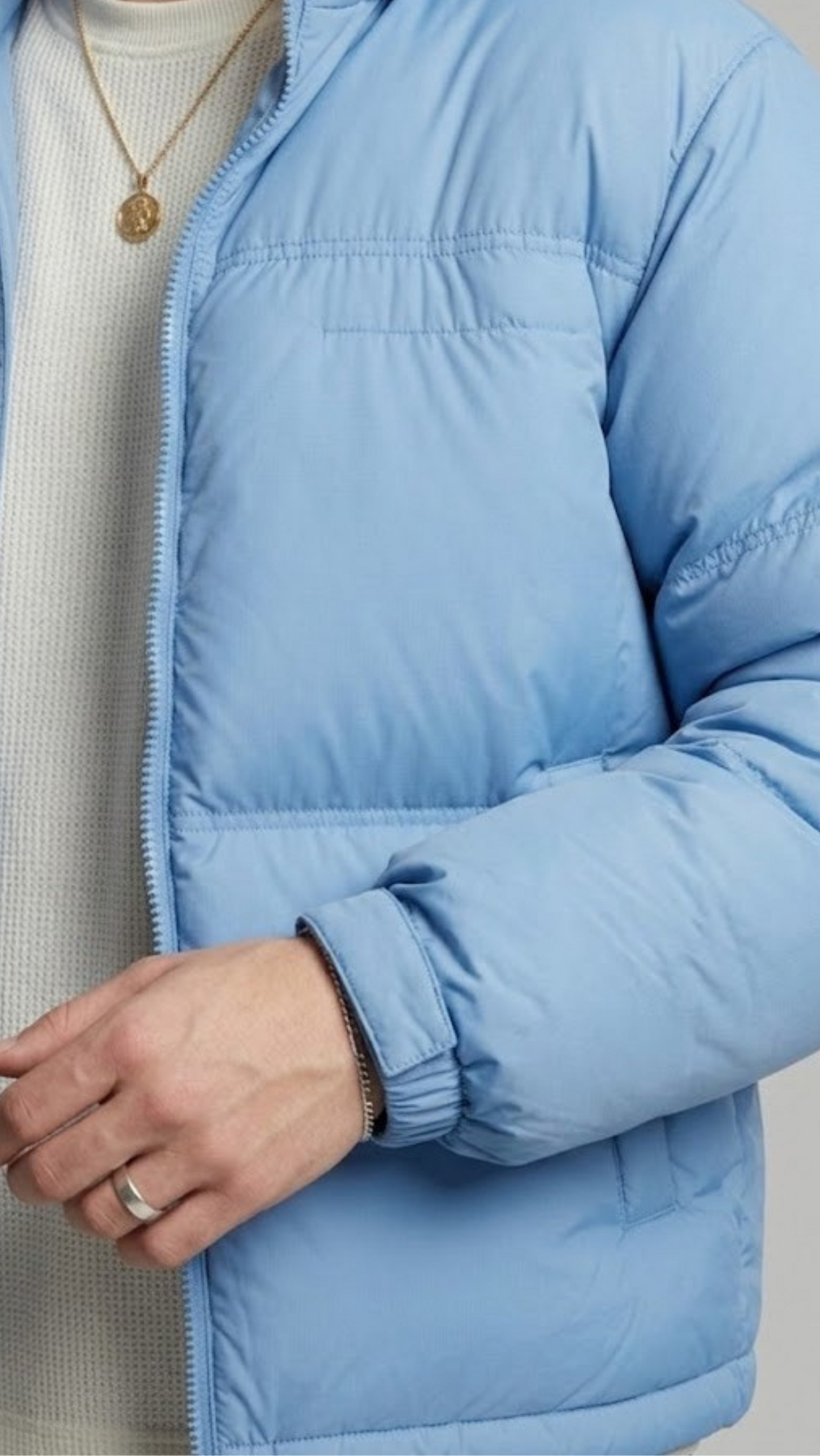 Light blue puffer jacket worn by a person on a neutral background