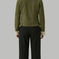 Person wearing a green jacket with a white collar and black pants on a gray background