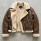 Brown leather jacket with beige shearling lining on a gray background