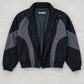 Flat lay presentation of Jackero black and dark grey oversized Y2K nylon jacket displaying internal lining and neck label