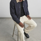 the premium matte snap buttons and dense dark blue cotton weave texture on the front placket of the coach jacket.