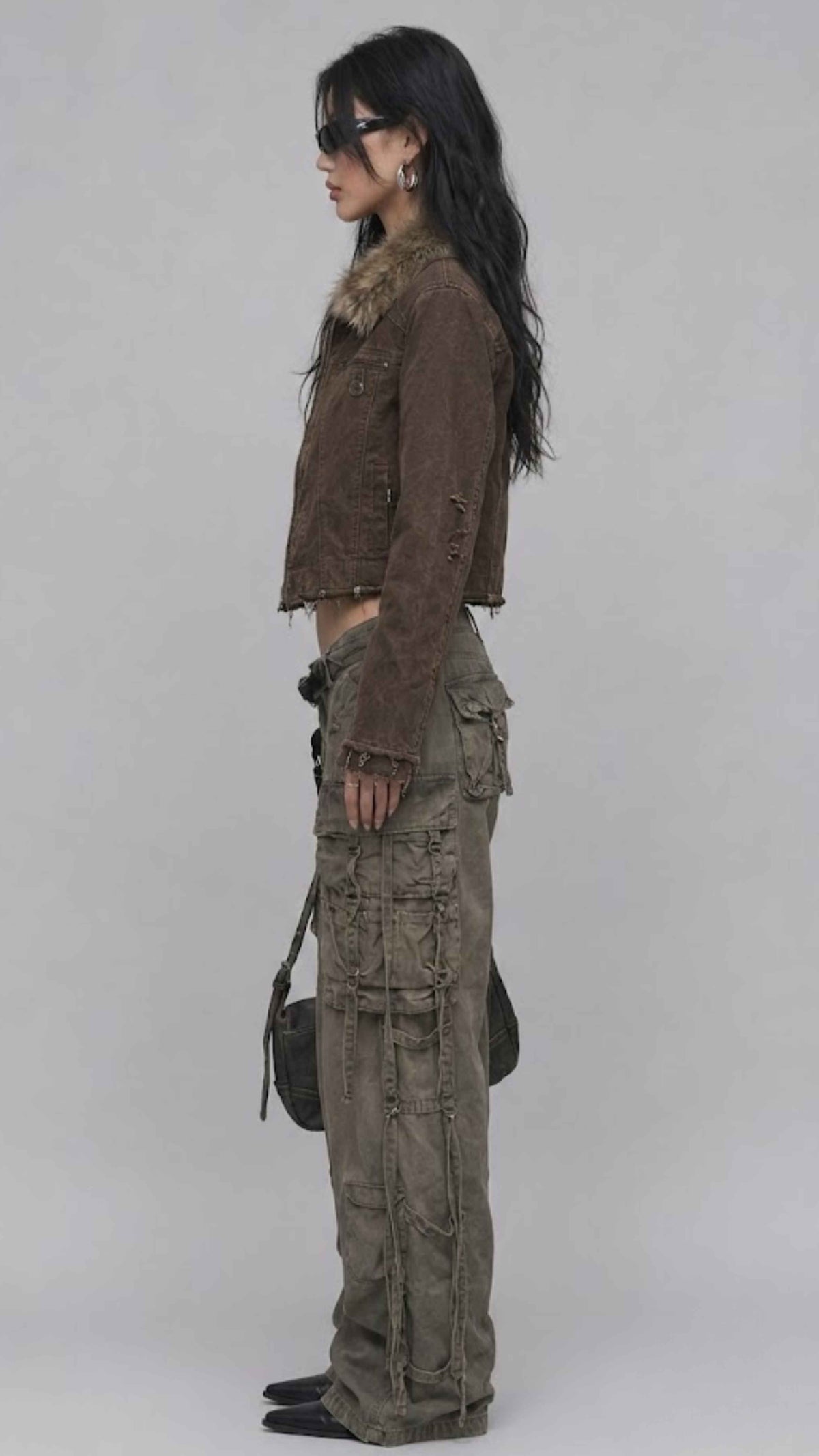 Side angle of model wearing dark khaki denim jacket with fur collar, displaying cuff buttons and relaxed fit