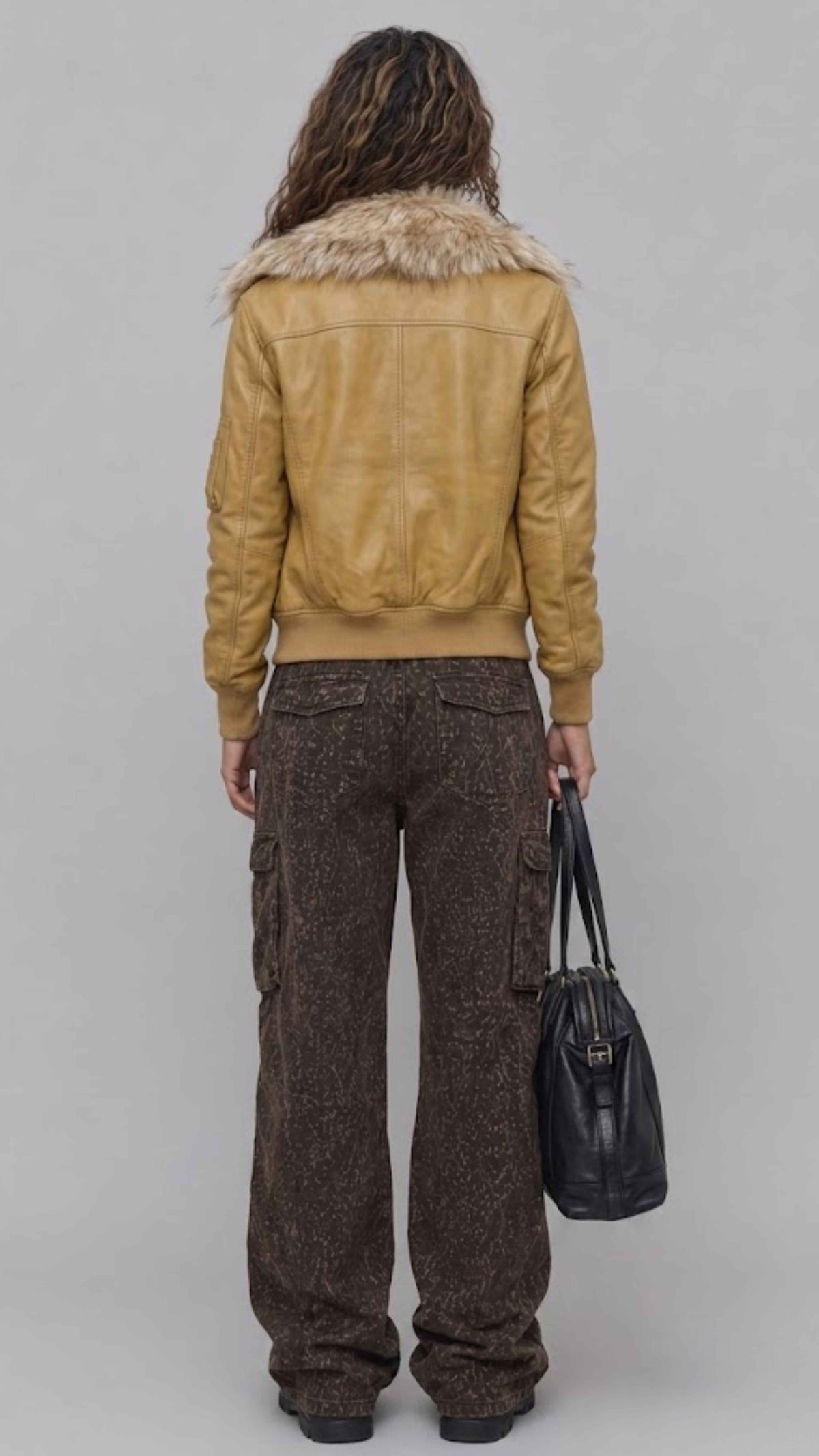 Rear view of women dark mustard leather jacket displaying precision panel stitching and tailored shoulder fit