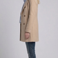 Elegant light khaki cotton overcoat layered beautifully over a casual outfit for a timeless smart-casual aesthetic.